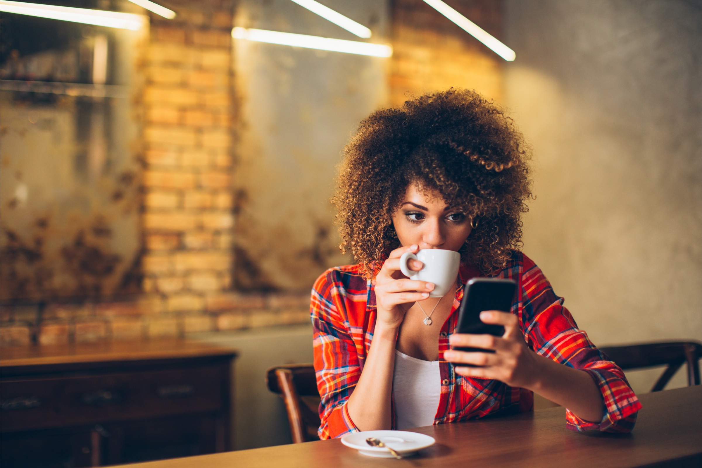 A relaxed woman drinking her coffee and easy accessing and using personalized banking services through her phone
